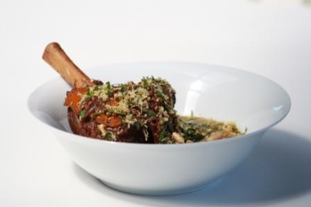 SLOW COOKED LAMB SHANKS SCATTERED WITH ROAST ALMOND PARSLEY AND LEMON GREMOLATA.
